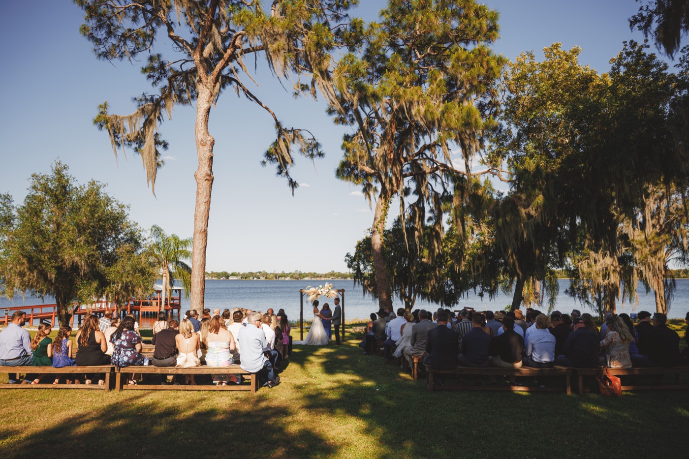 A wedding ceremony beneath the trees overlooking Lake Clay