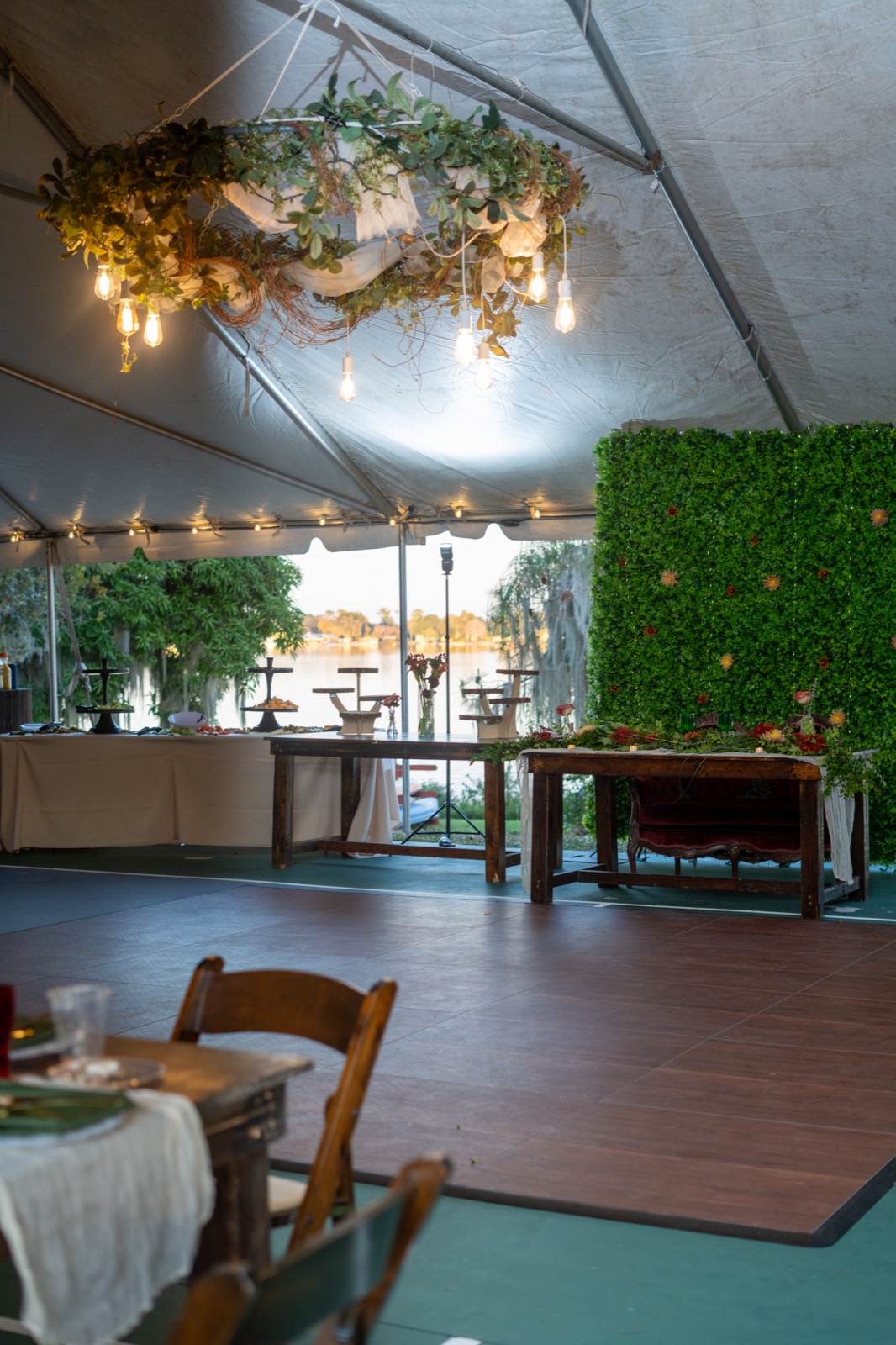 A wedding reception tent with a dance floor and a view of Lake Clay